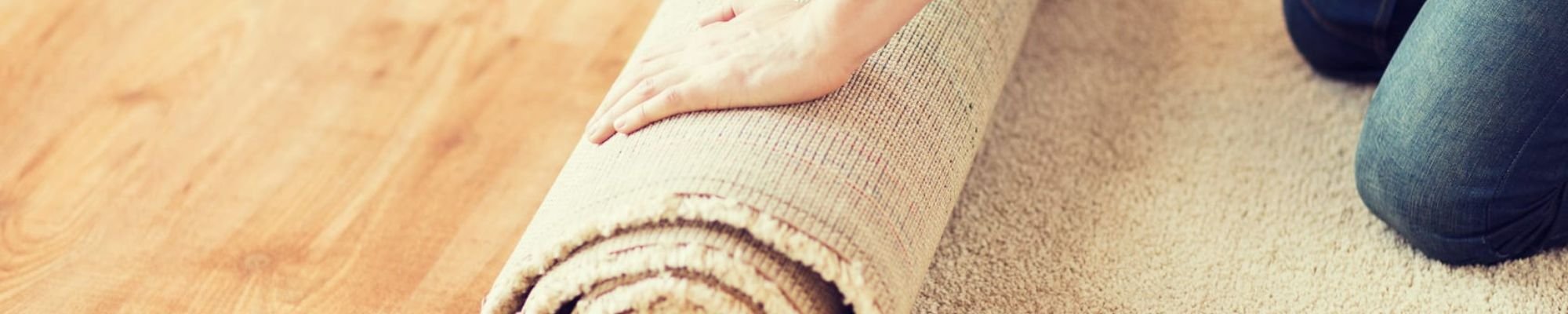 A person rolling a carpet down on laminate floors